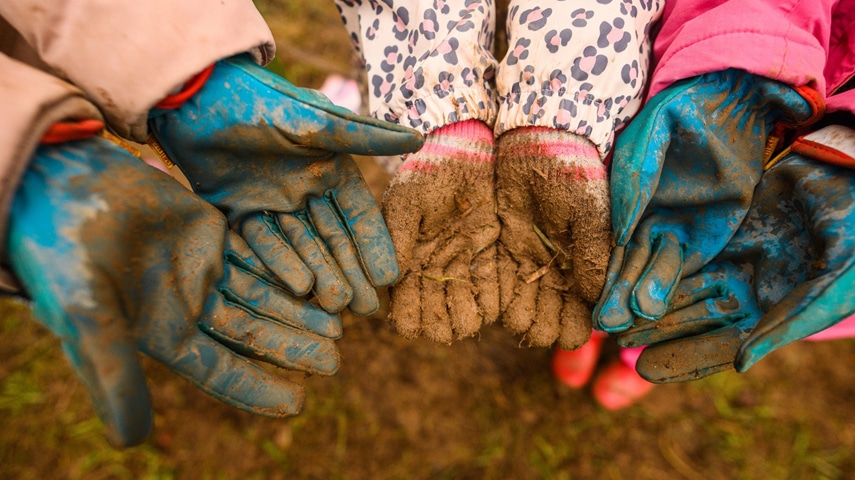 Three people showing their muddy gloves