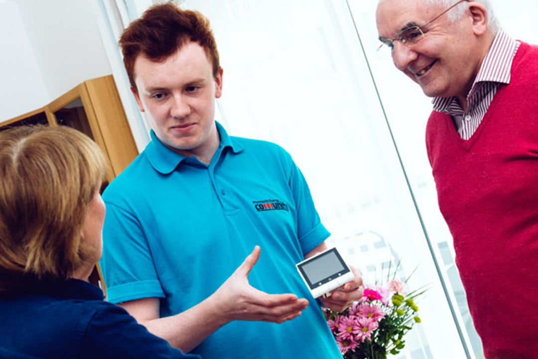 Plymouth Energy Community advisor explaining a heating system to an elderly man and woman
