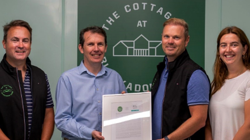 The Cottages at Blackadon Farm team standing in front of their logo holding their Green Tourism certificate