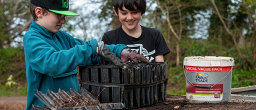 Two friends potting up tree saplings at Moor Trees's Dartington Nursery