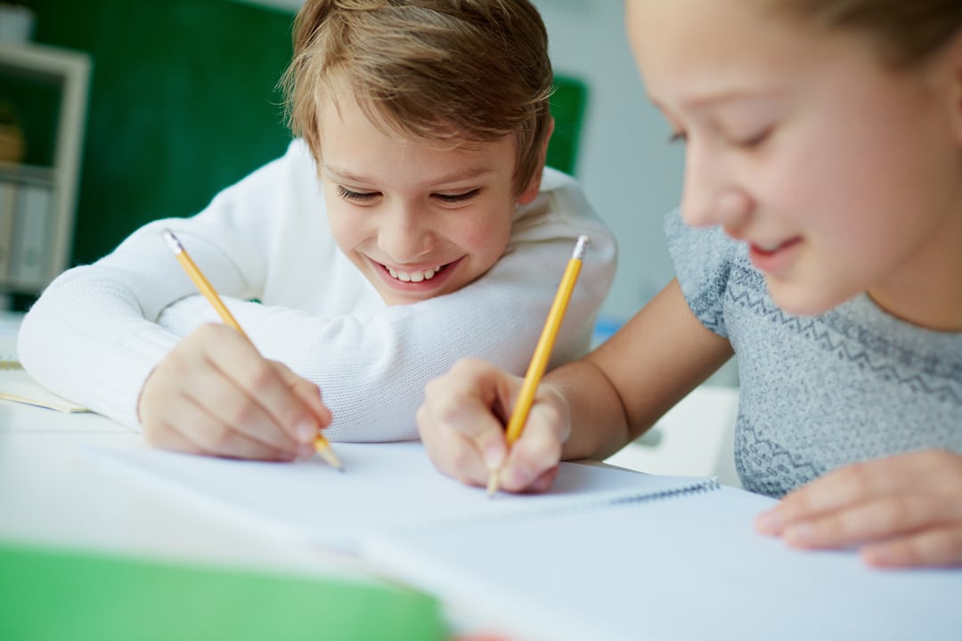 Classmates writing in the same notebook